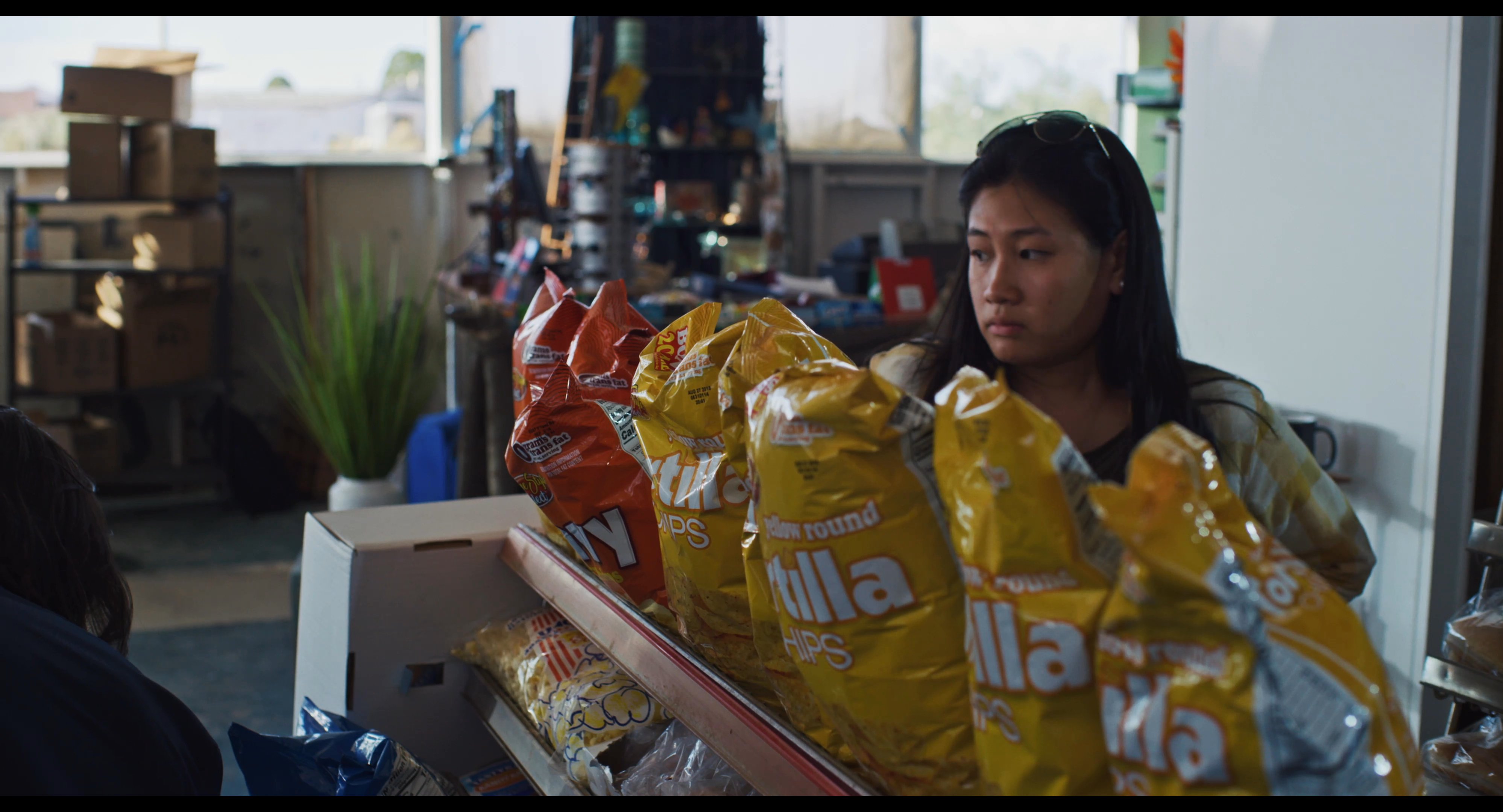 Two retail staff members collaborate to organize and restock snack merchandise on store shelves.