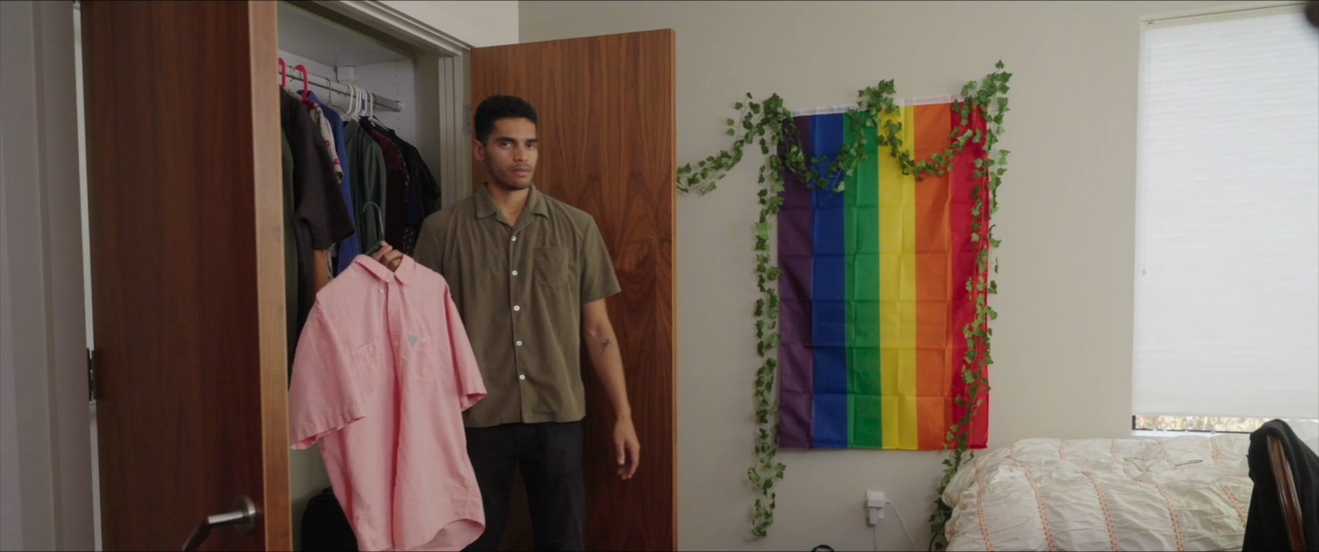 A man evaluates clothing options in his bedroom closet before choosing a shirt and preparing for his day.