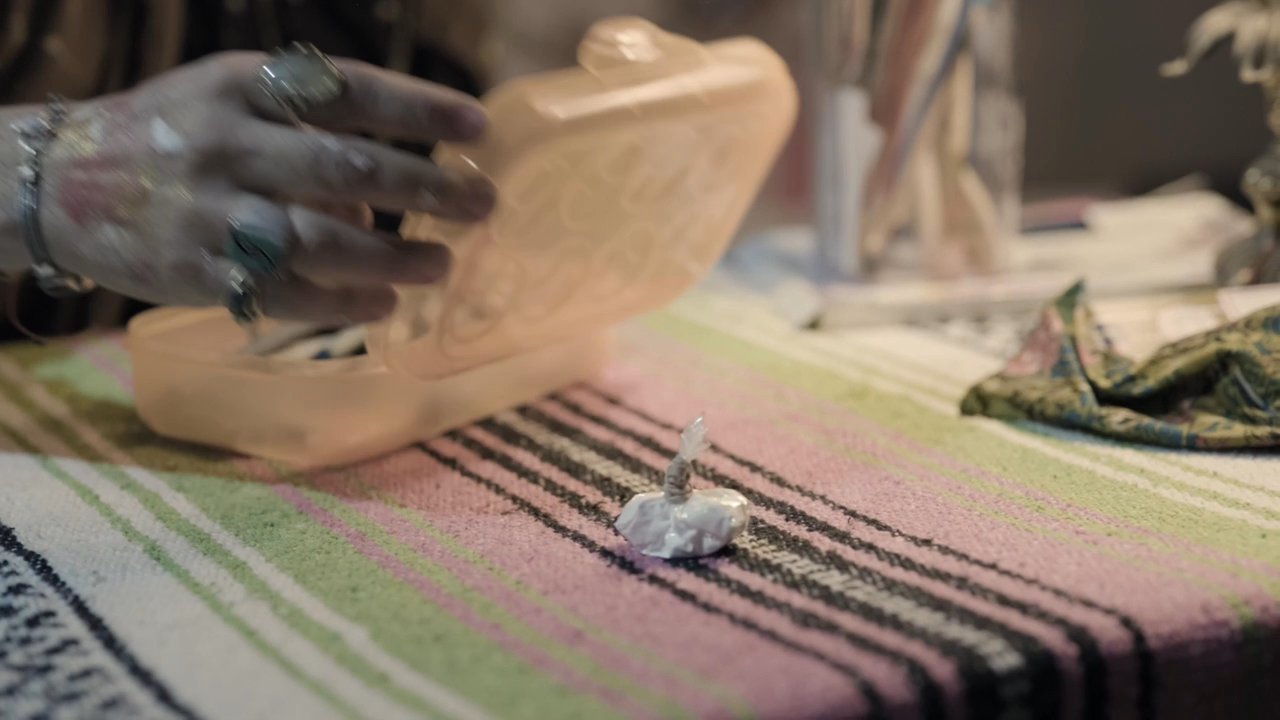An artist carefully organizes painting supplies on a workspace table in her studio. She completes the task and prepares to leave the creative space.