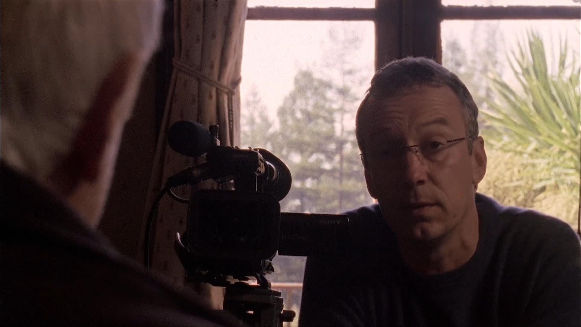 A film crew captures an interview with Dr. Ian Dunbar in a home library setting. The sequence shows the technical setup followed by the expert providing insights directly to the camera.