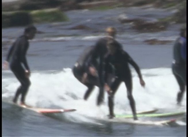 Instructors guide students on surfboards, demonstrating techniques while riding waves in the ocean.