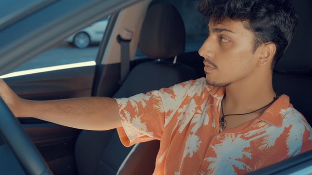 A teenage boy sitting in a car waiting for somebody