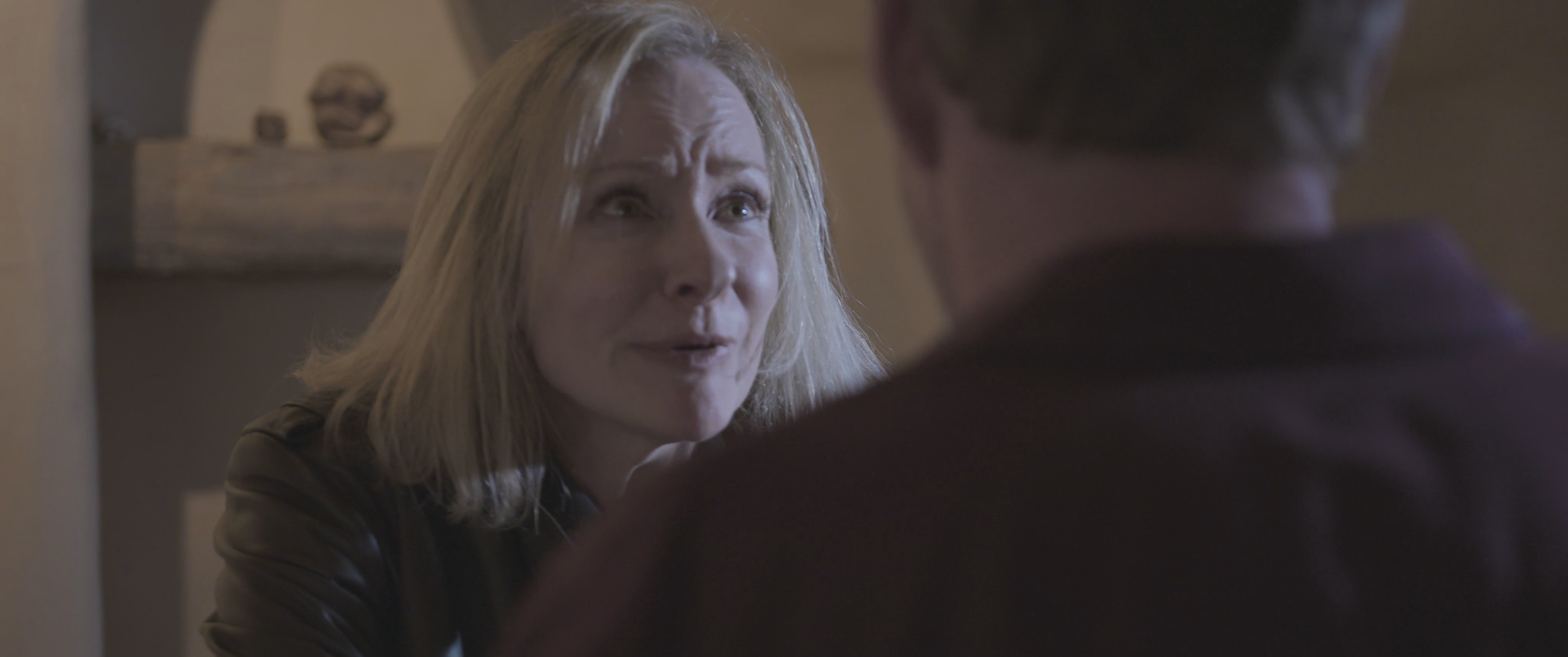 A man and a woman engage in a tense, emotionally charged conversation within a home environment. Their interaction reflects significant interpersonal conflict and verbal disagreement.