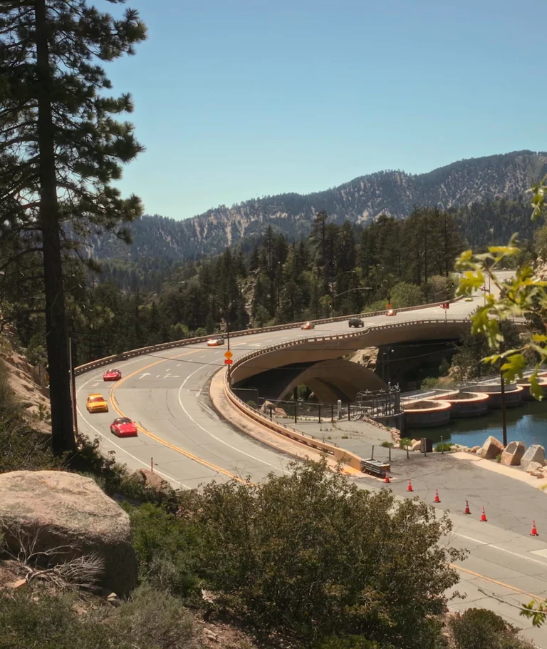Video of vintage cars driving in scenic area near Big Bear, California.