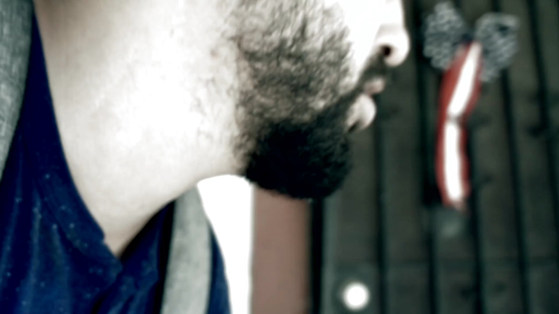 A man with a backpack gazes intently at his surroundings from a doorway before surveying an empty outdoor area. His focused demeanor suggests a state of heightened awareness or anticipation.