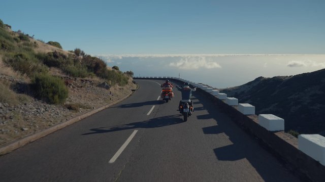 Bikers driving at a high altitude close to a mountain peak 