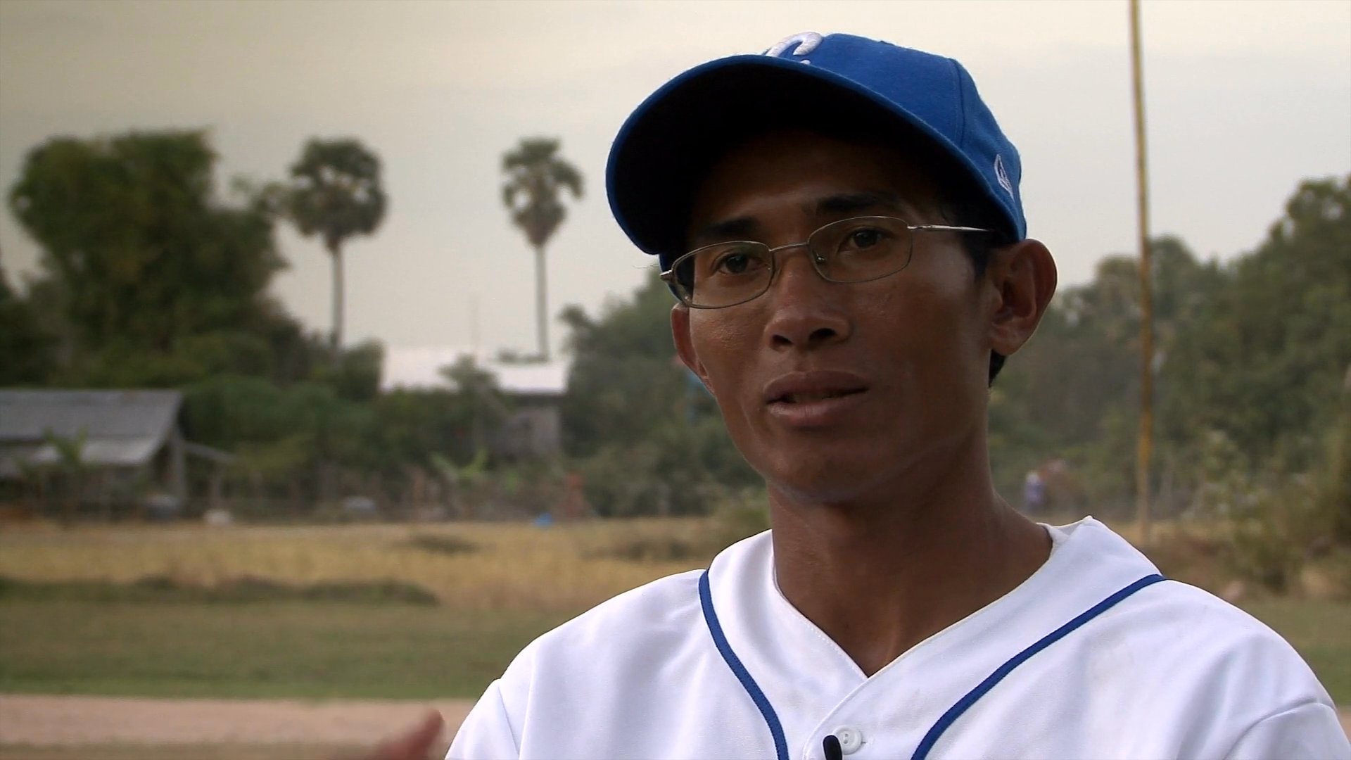 Young athletes participate in baseball practice under the guidance of a local coach while historical footage illustrates the broader context of the region. The narrative highlights the growth of the sport through community engagement and structured training sessions.