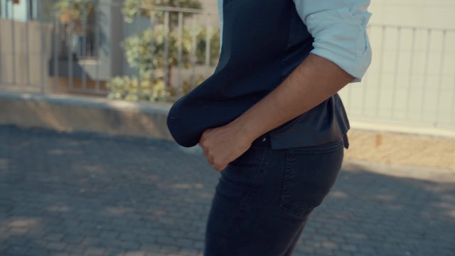 A man getting his phone from his pocket while walking along a street