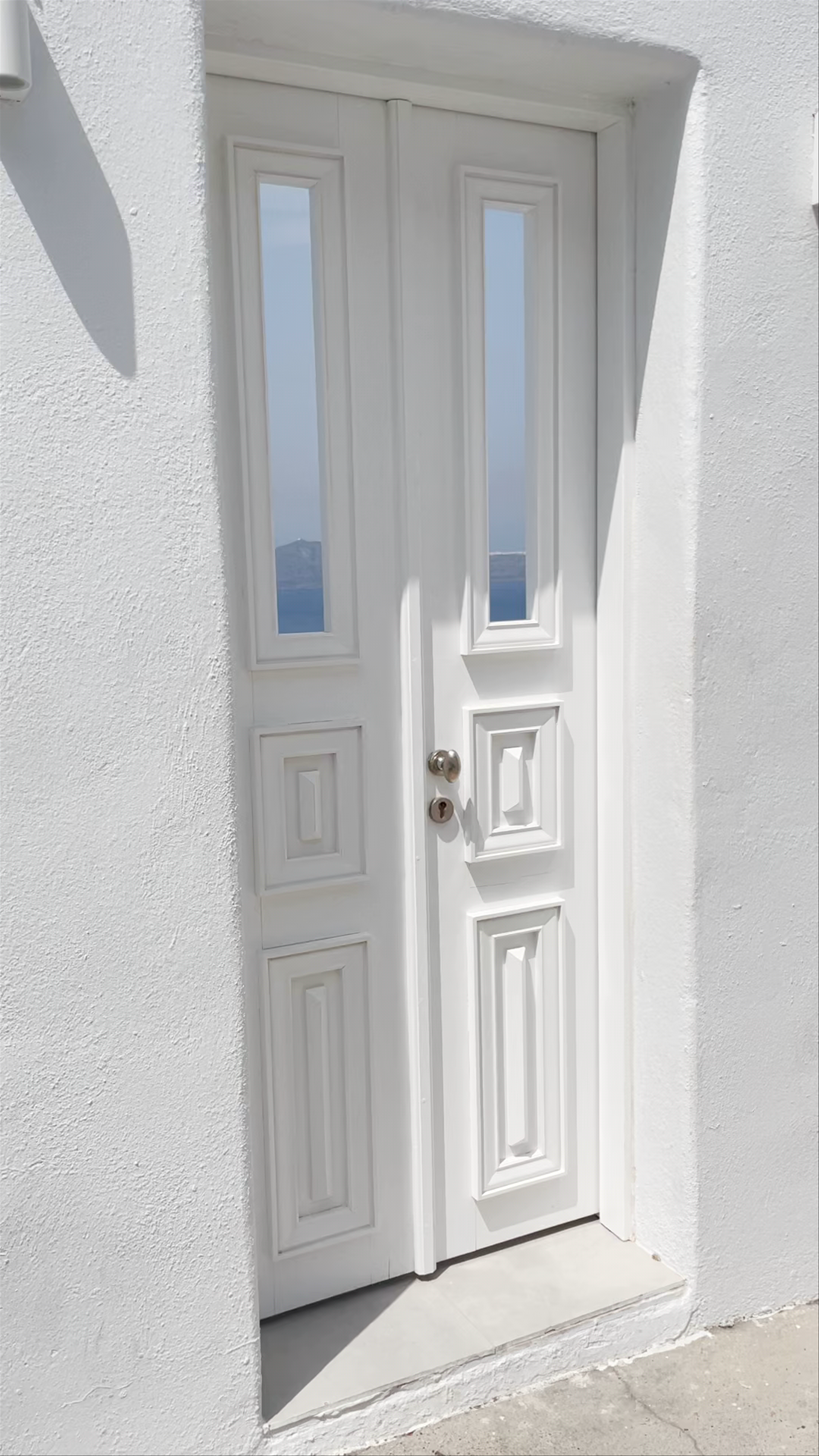 Sunlit Serenity: White Doors and Stunning Caldera Views in Fira, Santorini