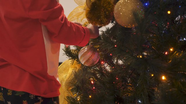 Boy hangs decoration on Christmas tree
