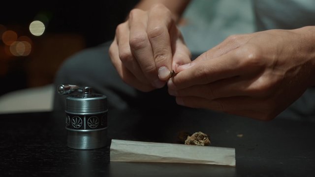 A man rolling a paper filter for a marijuana joint