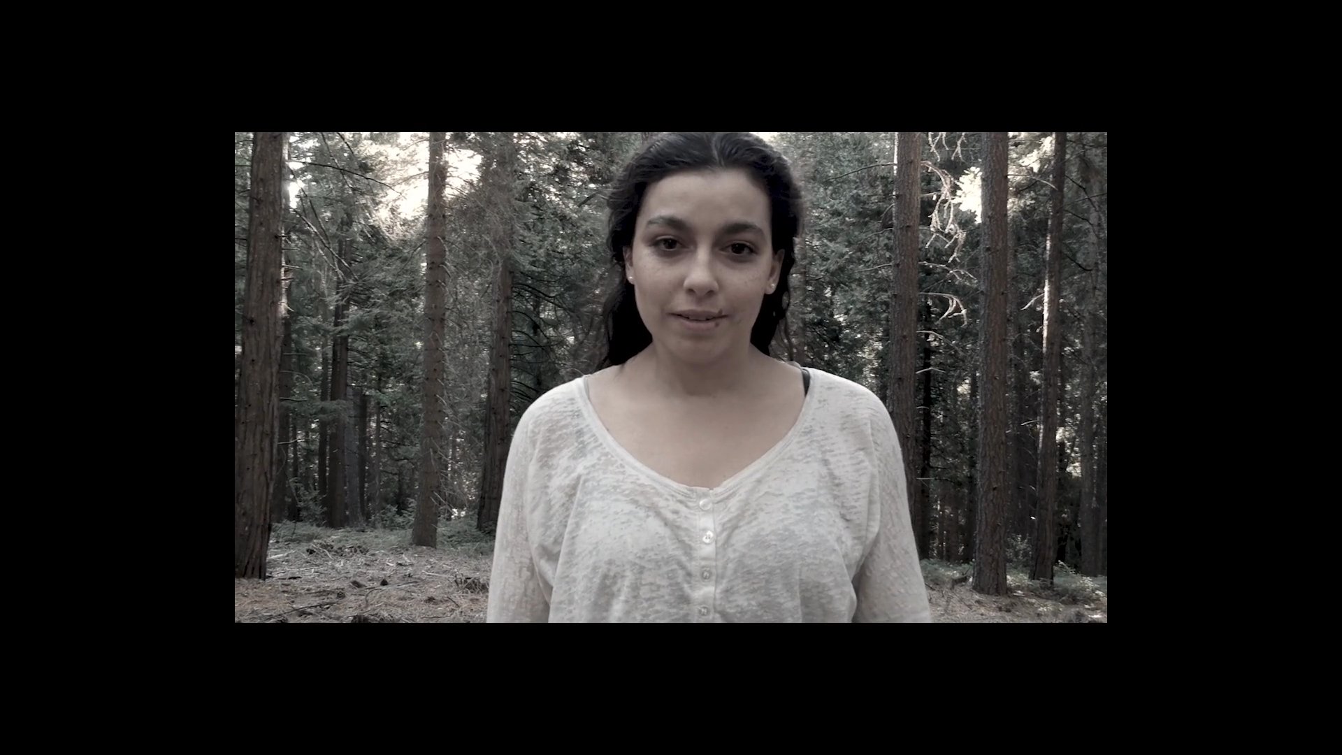 A woman operates a drone in a forested area, managing its takeoff and monitoring its flight path. The scene captures the integration of modern technology within a natural environment.