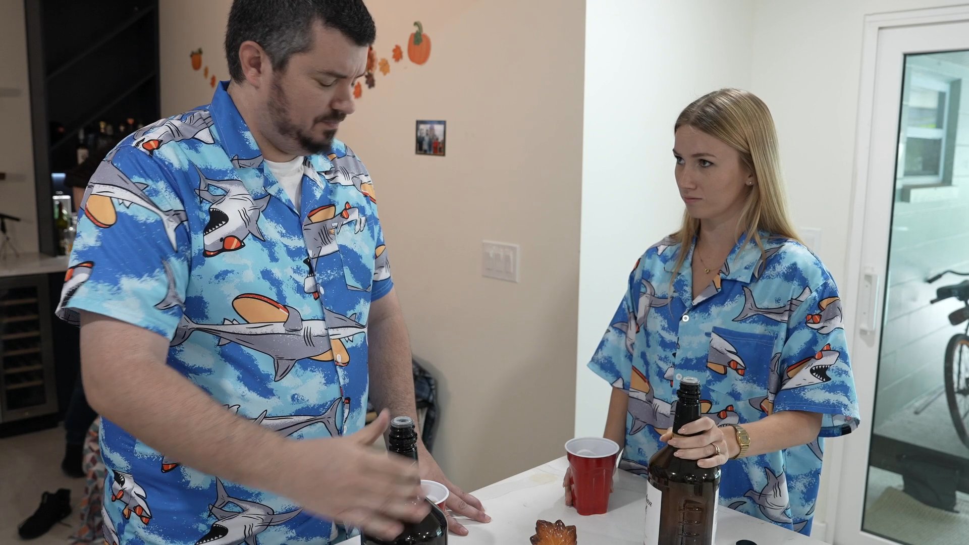 Two individuals in casual attire compete in a drink-based social game, concluding with a high-five upon completion.