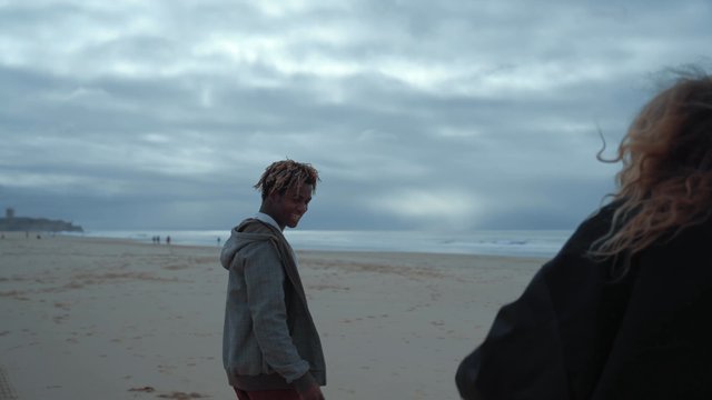 A girl taking photos of her male friend at the beach