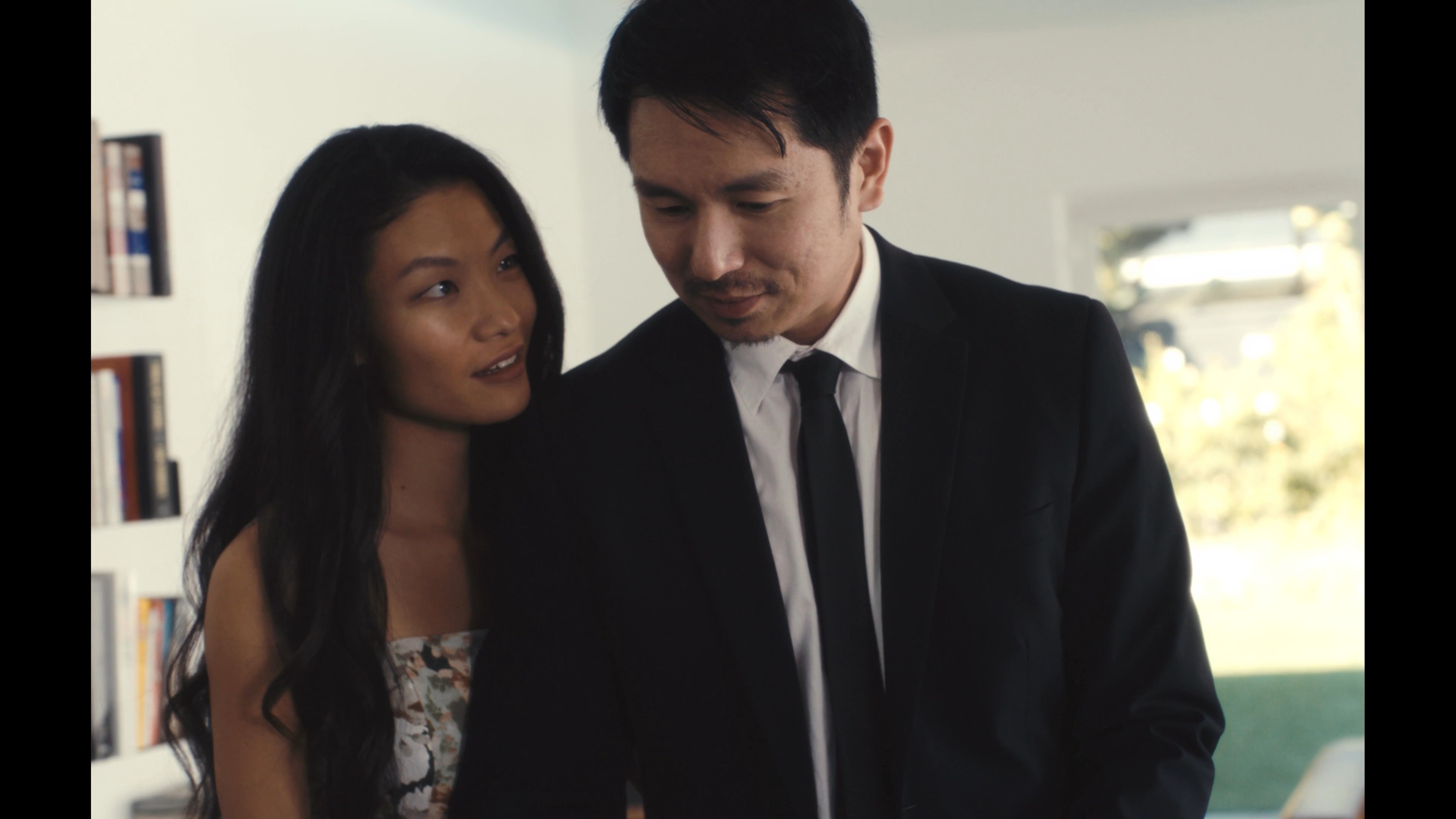 A man and woman navigate complex emotional moments, transitioning between domestic intimacy and a stylized, surreal environment bathed in red light. These shifting scenes suggest an exploration of internal conflict or subconscious states within their relationship.