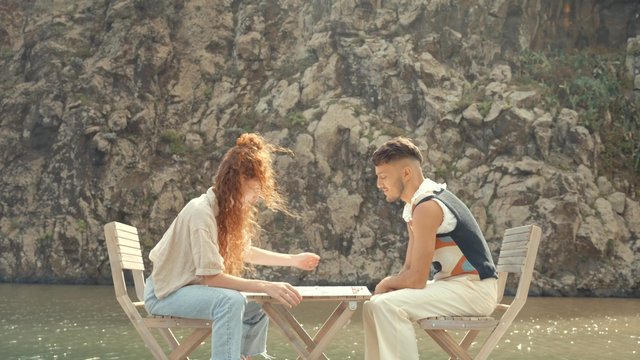 Two friends sitting at a table and playing a board game outside