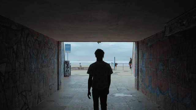 A man walking through a tunnel to the beach
