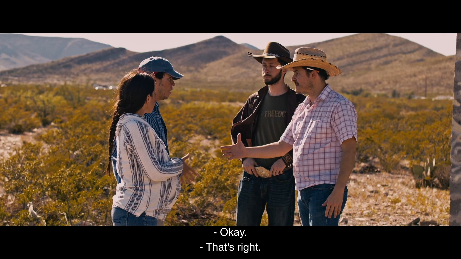 A group of individuals negotiates a illicit package transport deal in a remote desert landscape, while one participant insists on a prior apology for theft.