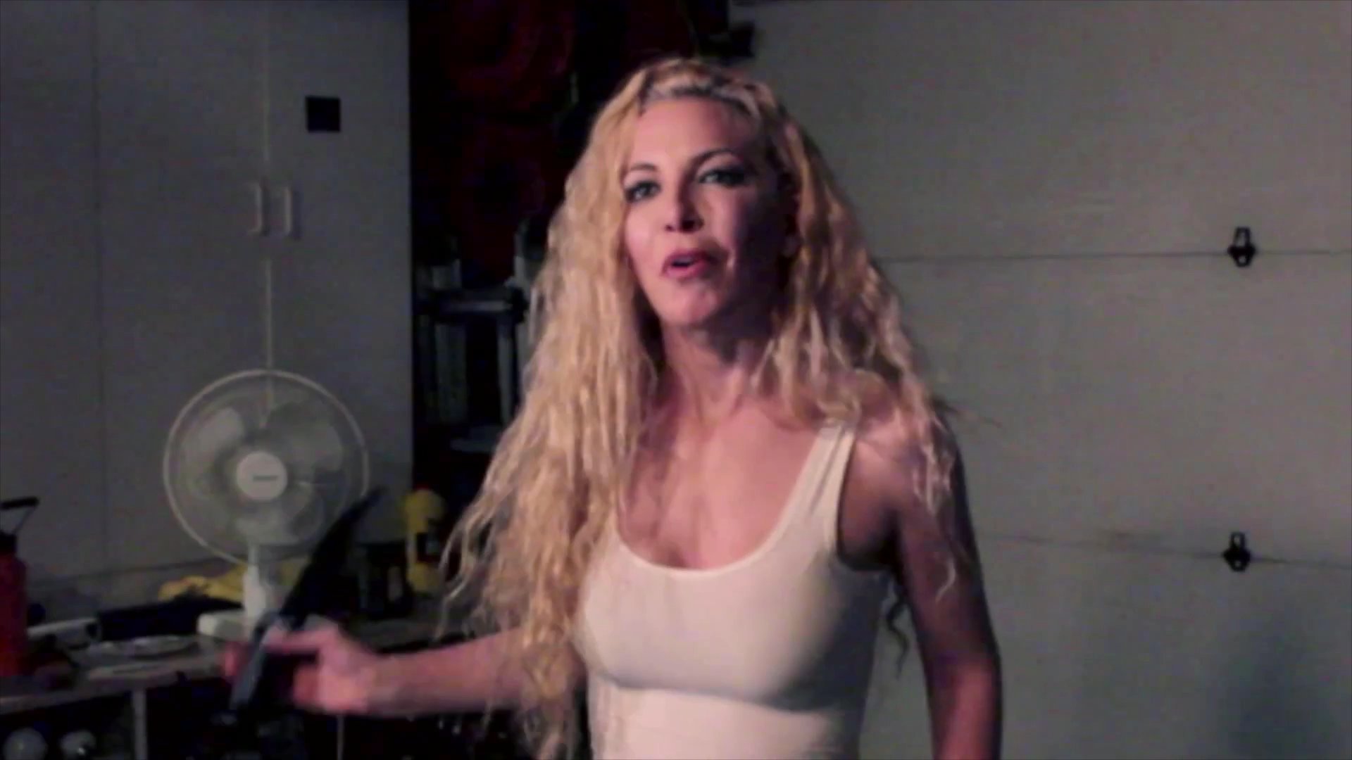 A man and a woman engage in a tense, high-energy sequence within a garage setting, shifting between aggressive movement and stationary dialogue.