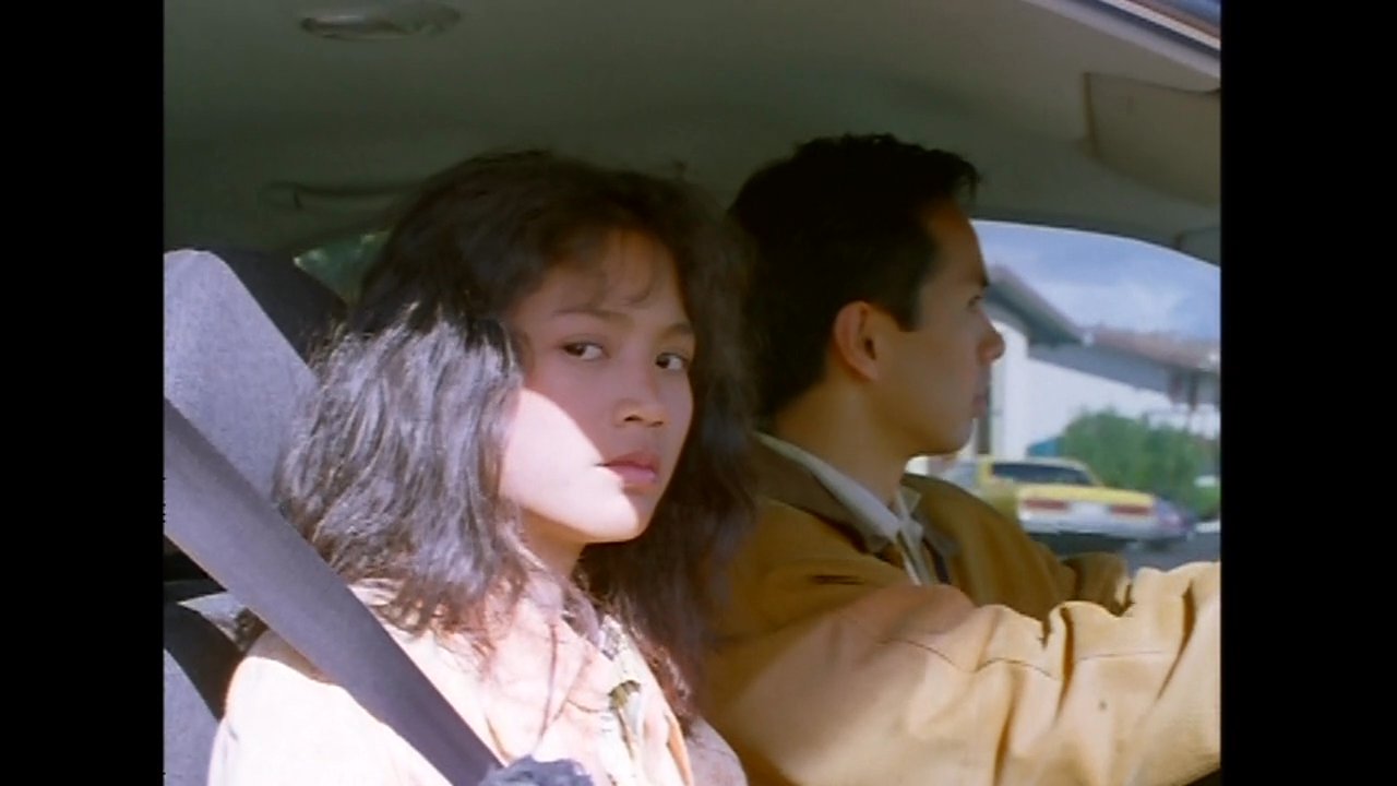 Individuals travel in vehicles through a busy commercial street, observing the surrounding storefronts while navigating traffic.