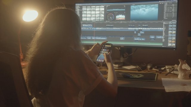 Video editor using her phone during a short break in her work area.