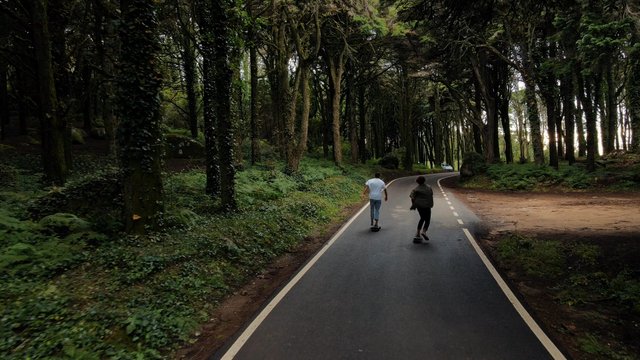 Friends skateboarding on the road in a forest