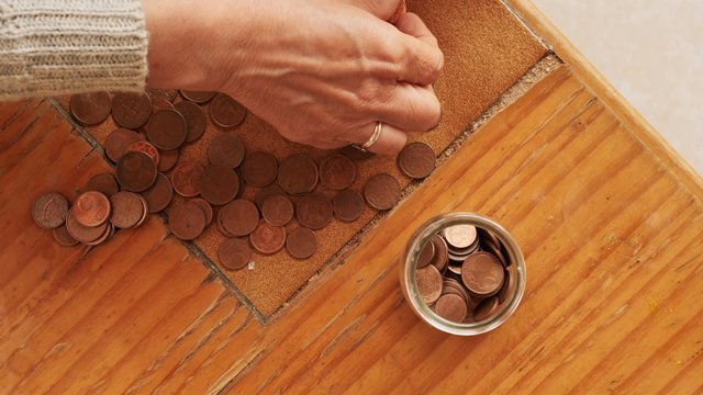 Woman picking up coins to put in a jar 