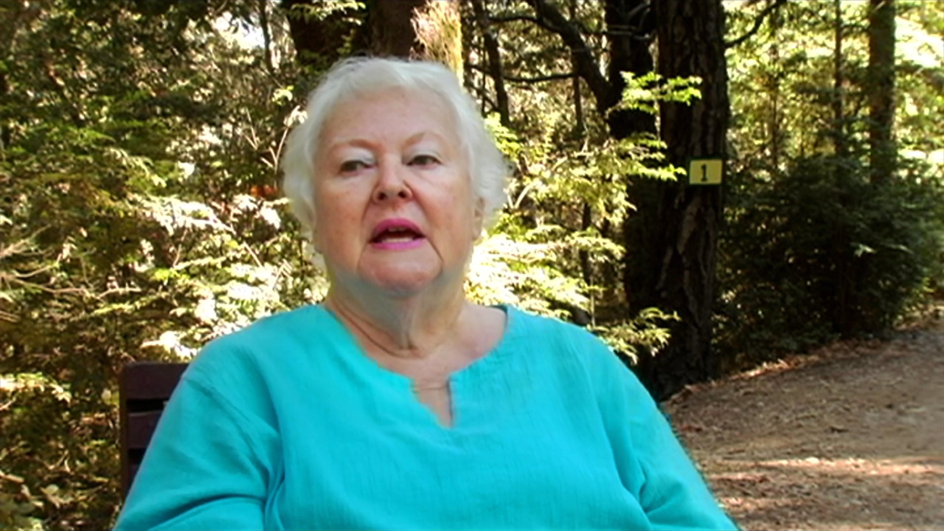 An older woman shares stories and reflections while seated in a wooded setting, interspersed with footage of long-haired bikers with their motorcycles. The segment captures a narrative contrast between personal recollection and the rugged lifestyle of the motorcycle community.