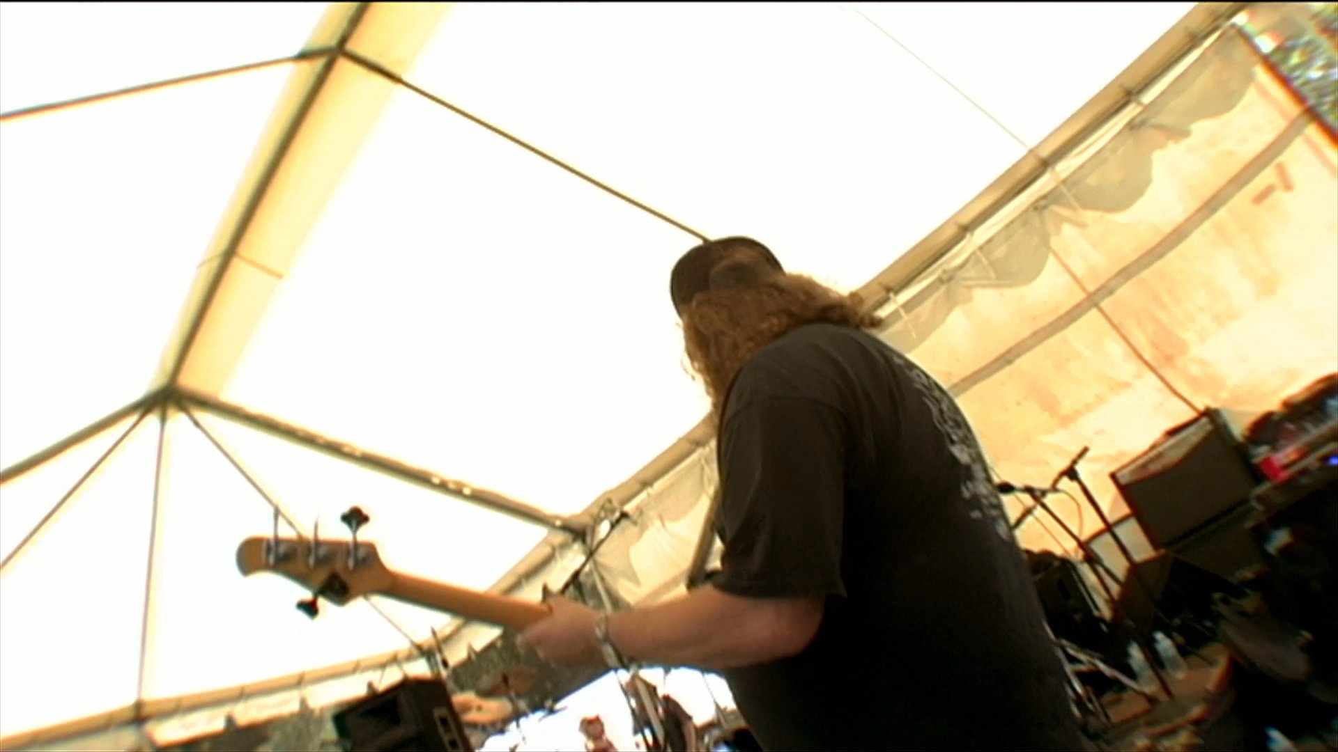 A man provides commentary at a motorcycle event while a live band performs on an outdoor stage for a crowd of enthusiasts.
