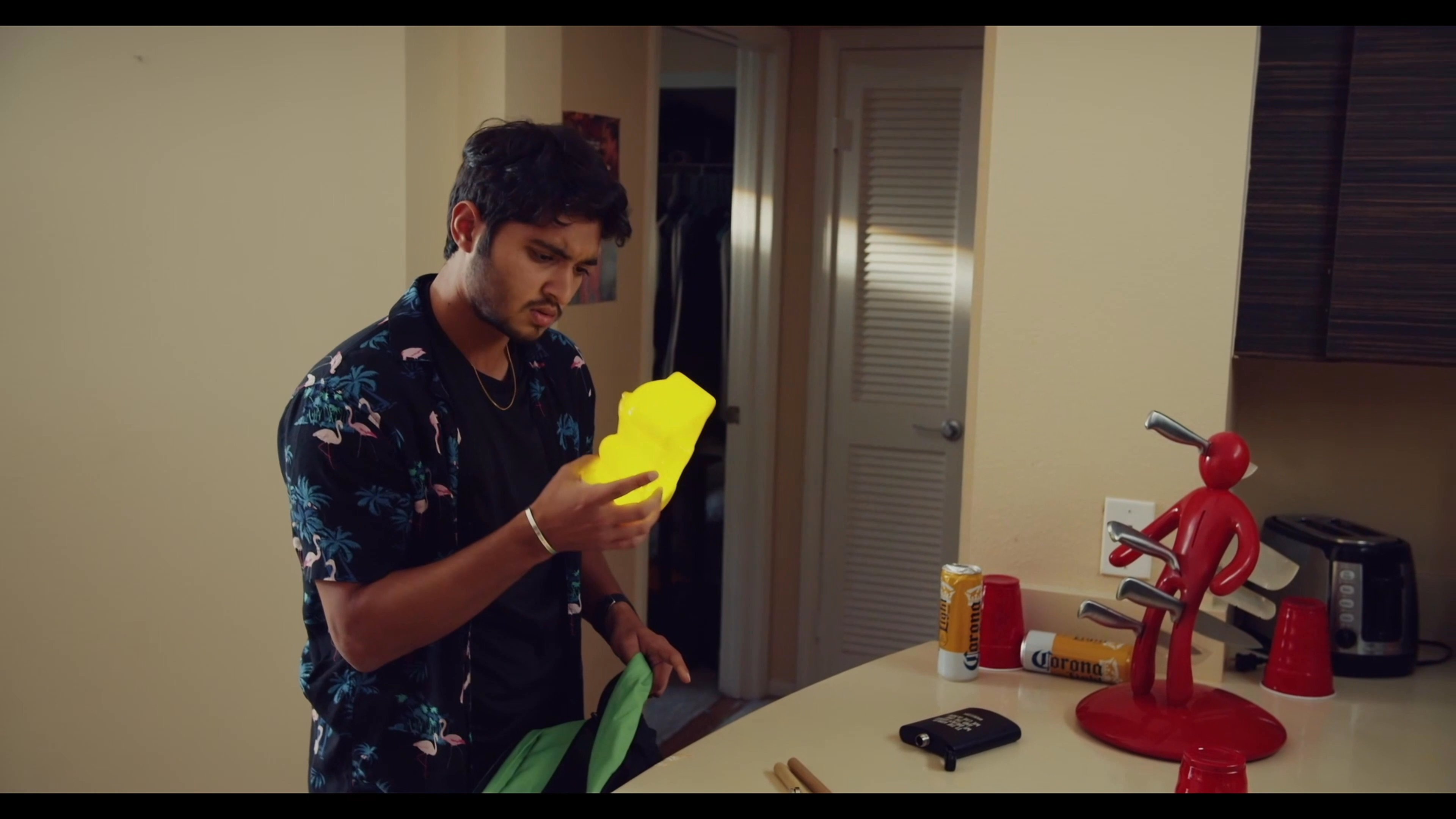 Two individuals participate in a casual game of darts in a domestic setting, alternating turns between throwing darts at a wall-mounted poster and preparing equipment at a table.