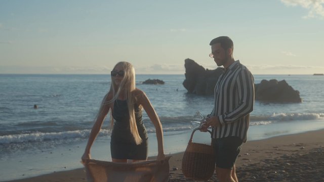 A beautiful couple setting up a picnic on the beach