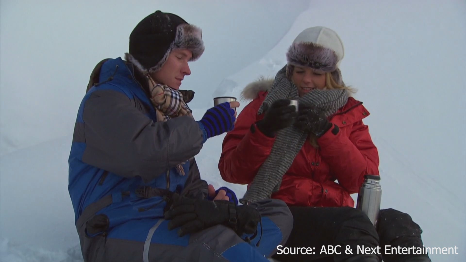 A couple shares a warm beverage during a snowy outdoor date while reflecting on their experience in individual interview segments.
