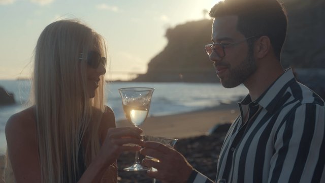 A couple on a romantic picnic date at a sandy beach at sunset