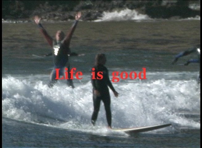A person in a wetsuit successfully rides a surfboard on an ocean wave. The scene captures the moment of accomplishment with the superimposed text, 'Life is good.'