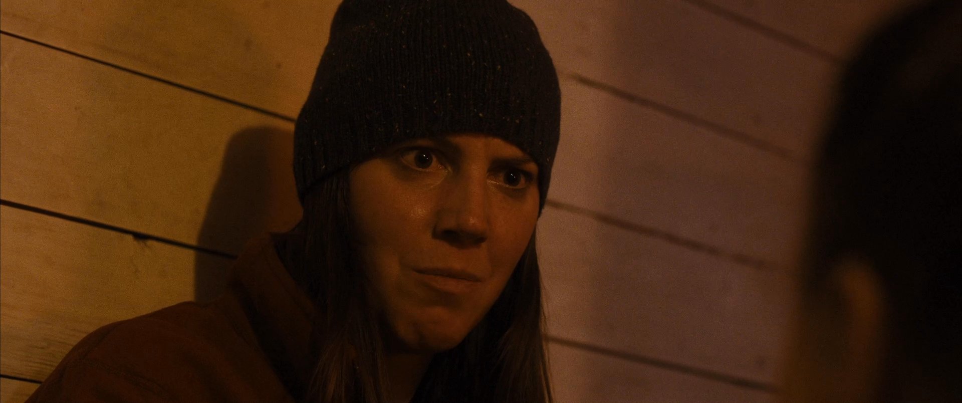 Two individuals engage in a heated discussion within a dimly lit room, which transitions to a scene featuring an injured person suffering from a head wound and showing visible signs of distress.