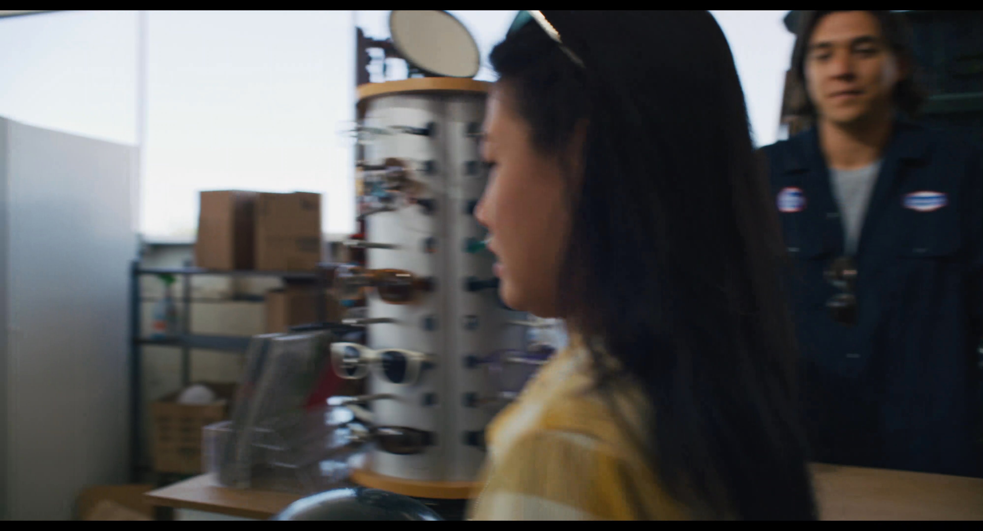 A store employee completes a transaction by handing a bowling ball to a female customer, who then exits the retail establishment toward her parked vehicle.