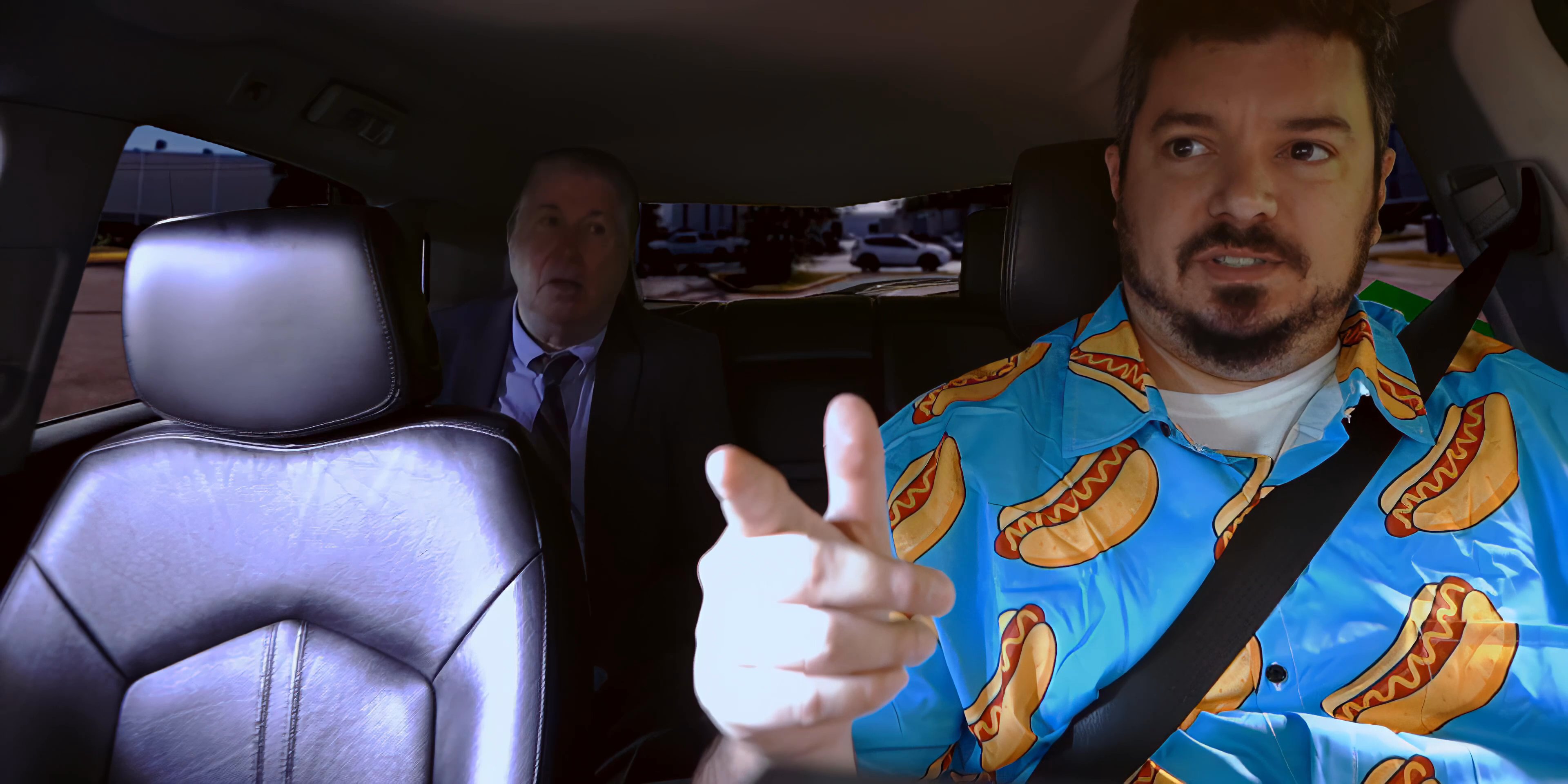 A man wearing a hot dog patterned shirt engages in a serious conversation with a passenger while driving during sunset, concluding with a scenic coastal view.