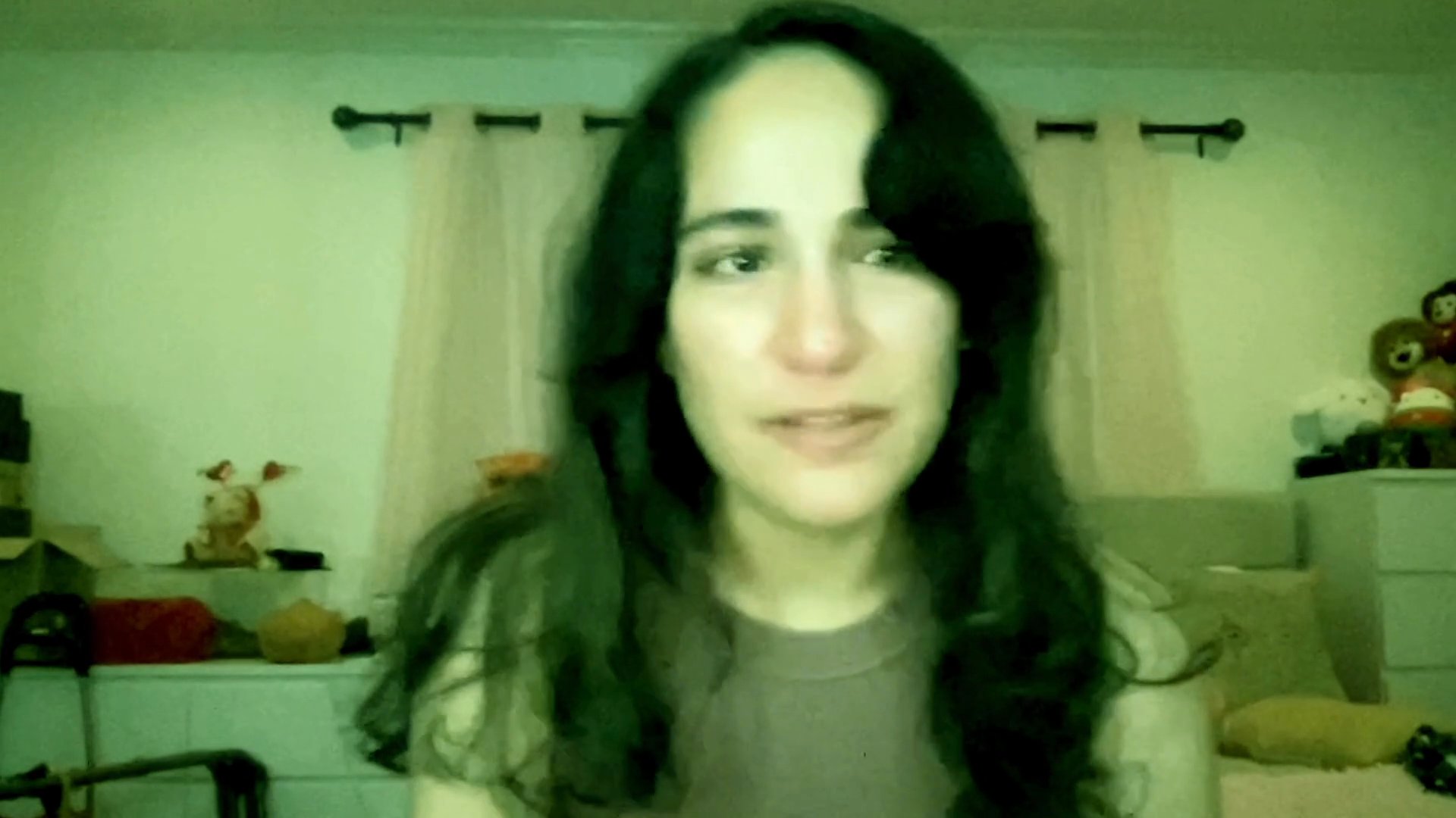 A woman speaks directly to the camera with visible distress and raw emotion, sharing a vulnerable personal experience from a bedroom setting.