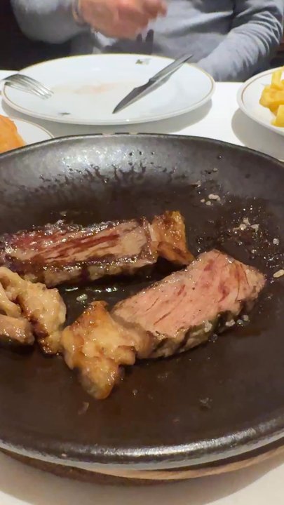 Mesón Txistu - Beef cooking on the cast iron at the table. - Basque Near Me - Madrid, M