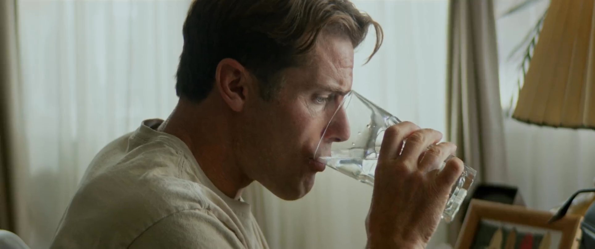 An author works in a quiet study, pausing to drink water before returning to compose on a vintage typewriter. The scene highlights the focused atmosphere of a creative workspace lined with classic literature.