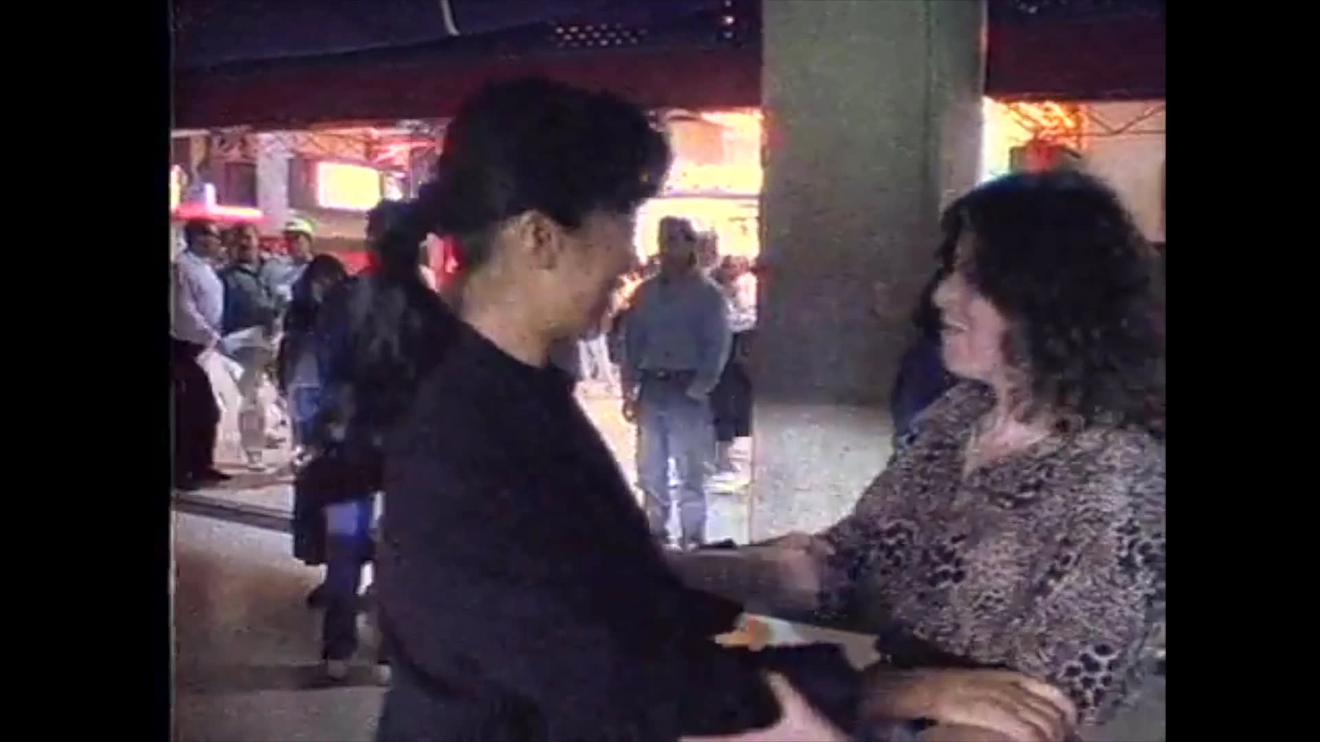 Individuals engage in tactile sign language at a baseball stadium, highlighting accessible communication methods within a public gathering space.