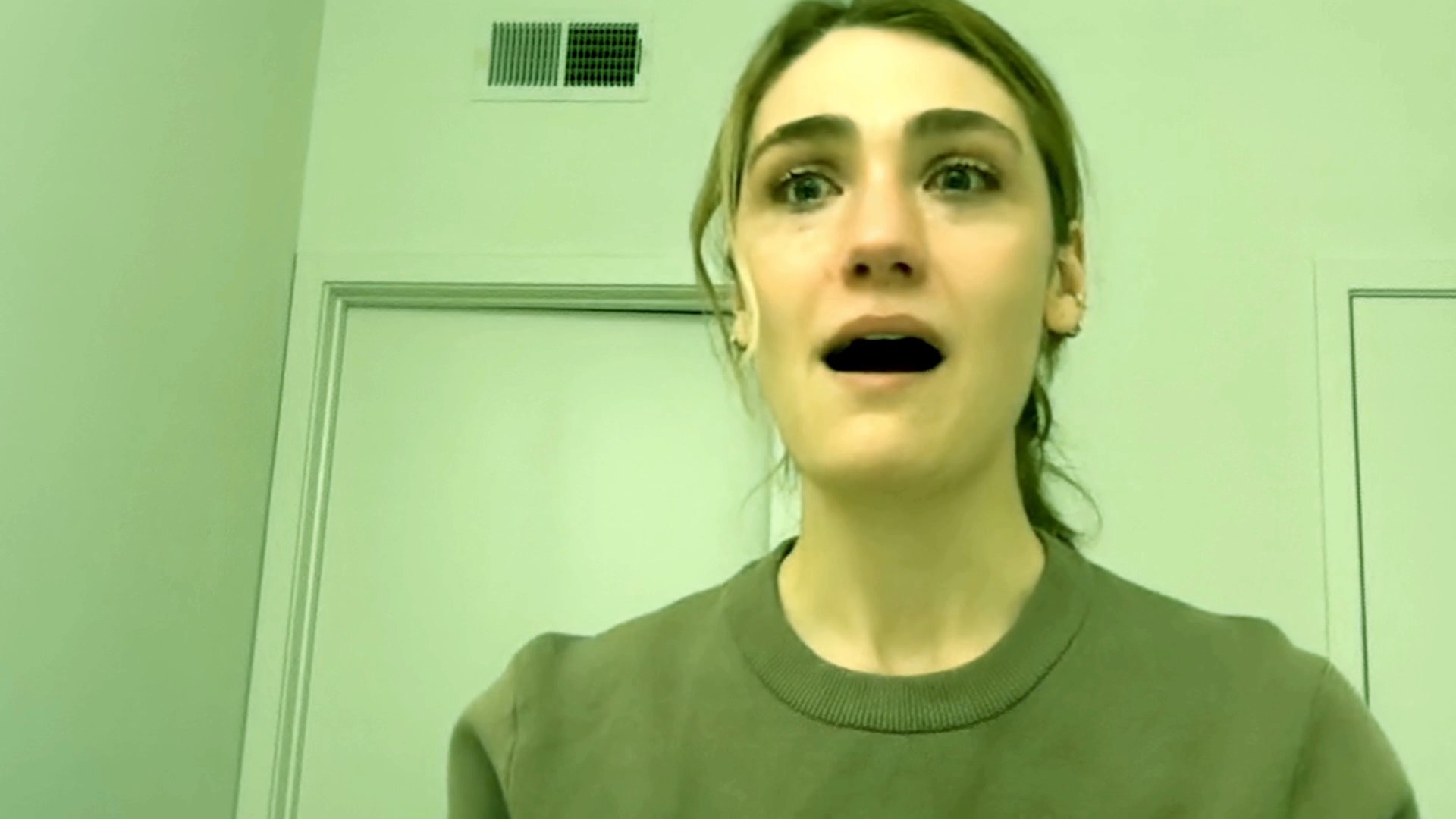 A woman exhibits visible signs of distress and emotional pain while looking directly into the camera. Her facial expressions fluctuate between sadness, contemplation, and overwhelm in a minimalist, green-toned environment.