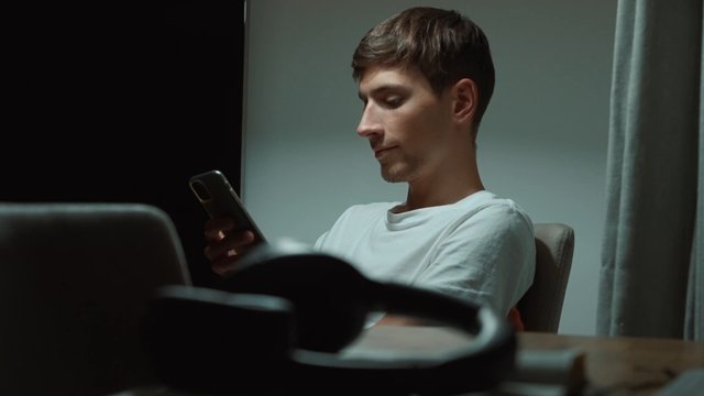 A man looking at his phone in his home late at night
