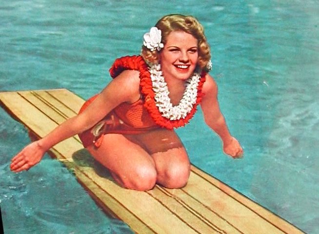 Historical footage documents surfing activities and transitions into a vintage magazine cover illustration featuring a woman on a surfboard. The visual progression highlights the mid-century aesthetic of water sports and physical fitness culture.