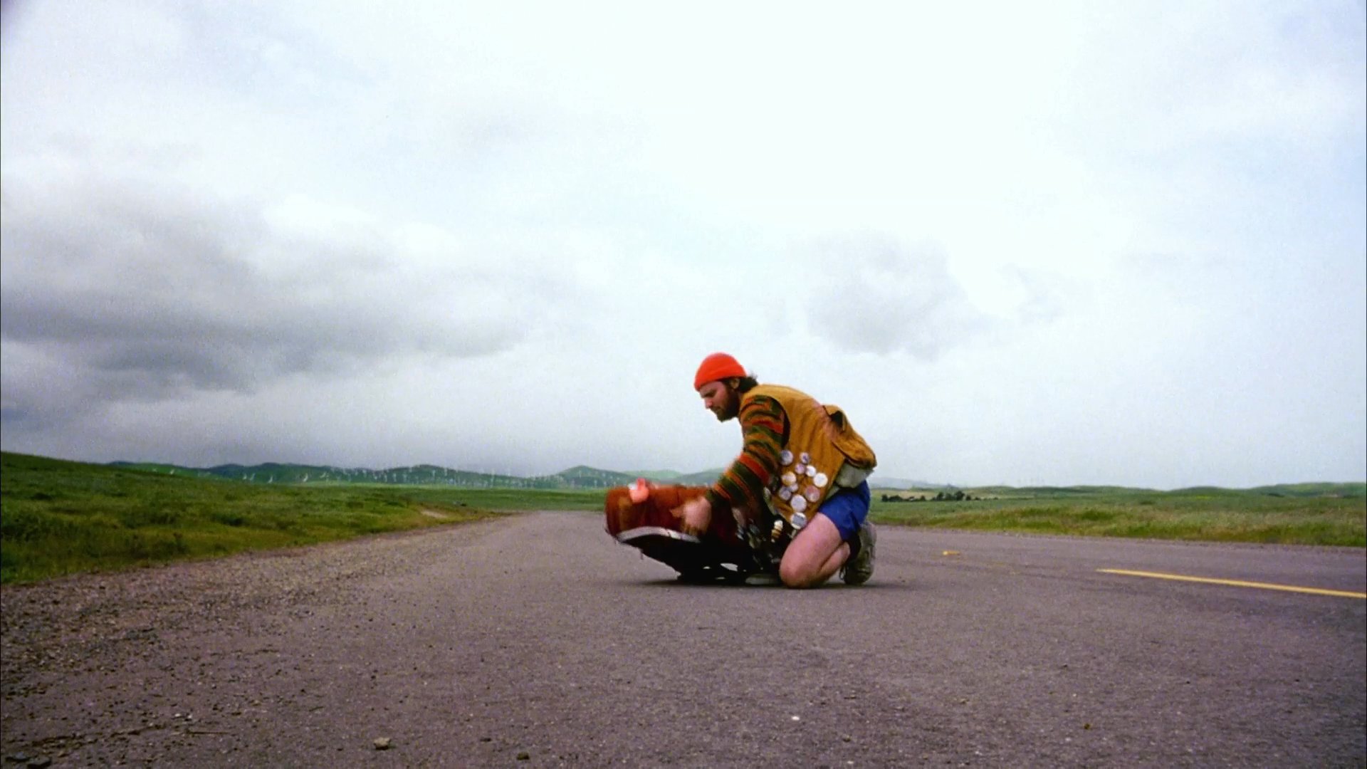 A traveler on a desolate rural road sorts materials into a specialized rucksack, organizing glass and plastic items from the roadside before continuing their journey.