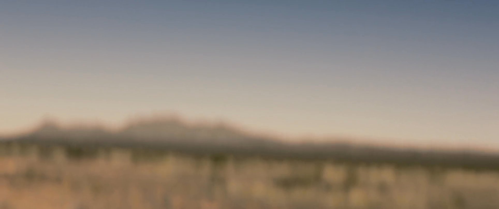 A man walks alone through an arid desert landscape, reflecting on a solitary journey across a vast, sun-drenched terrain.