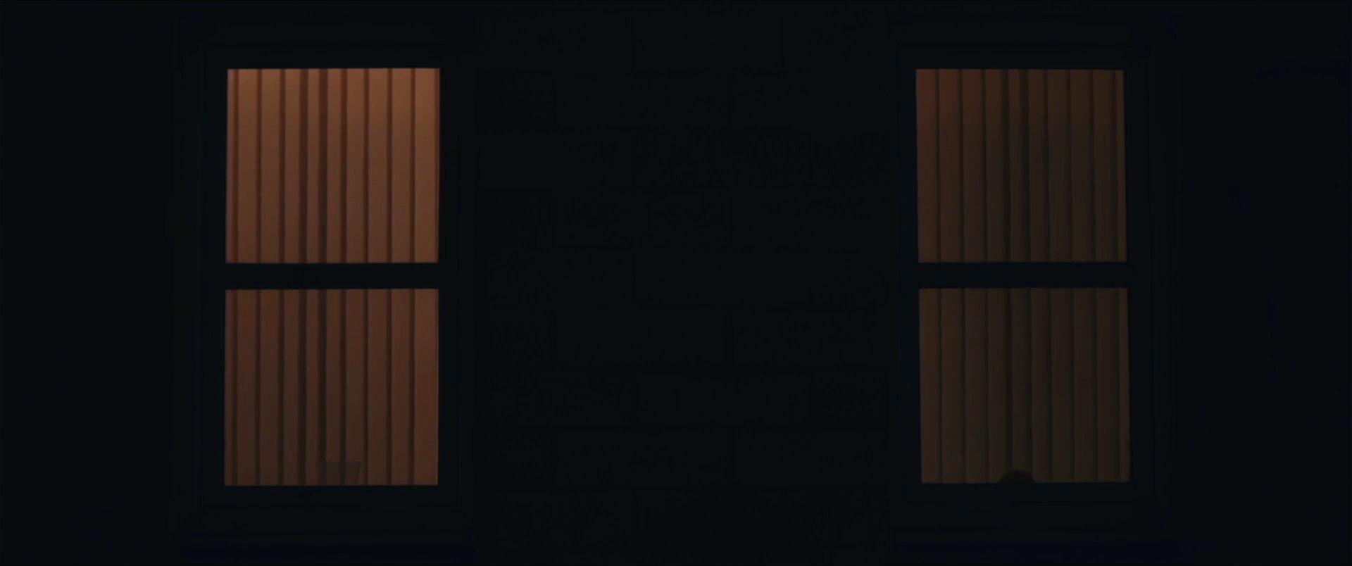 A teenager sits alone in a dim room checking his phone before transitioning to a quiet, intimate moment resting in bed. The scene shifts from isolated digital engagement to a calm, personal environment.