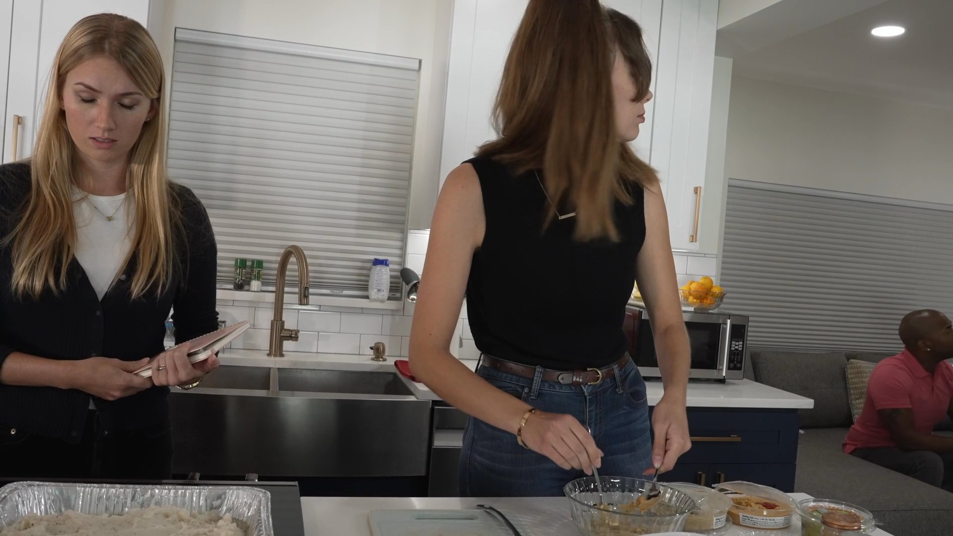 Three women collaborate in a home kitchen to prepare food, sharing guidance and ingredients during a communal cooking session.
