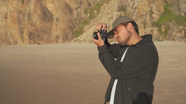 Man taking photos of the beach on a digital camera