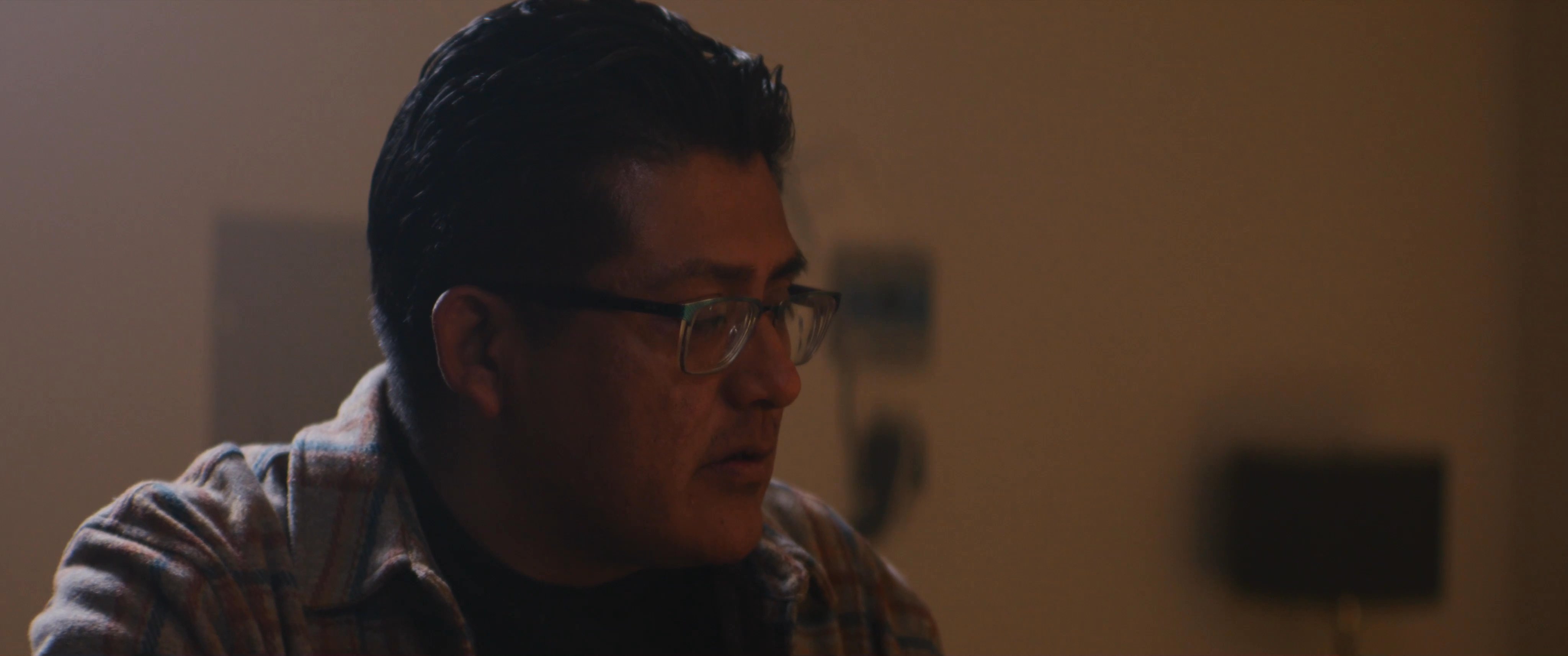 Individuals engage in a serious and focused discussion within a dimly lit studio setting. The participants exchange perspectives while collaborating on a project.
